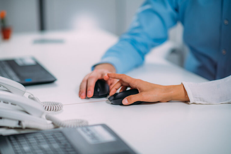 Un homme et une femme appuyant chacun sur un clic molette devant leur ordinateur dans un bureau.