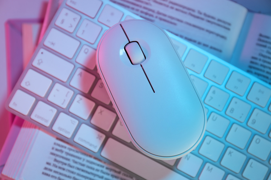 Une souris sans fil qui fait double-clic déposée sur un clavier externe de couleur blanc