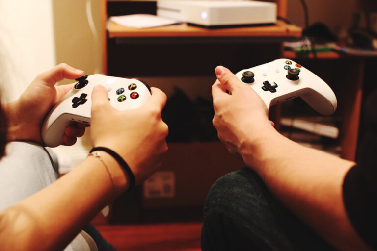 Deux hommes jouant aux jeux vidéo avec une manette xbox 360 et xbox one
