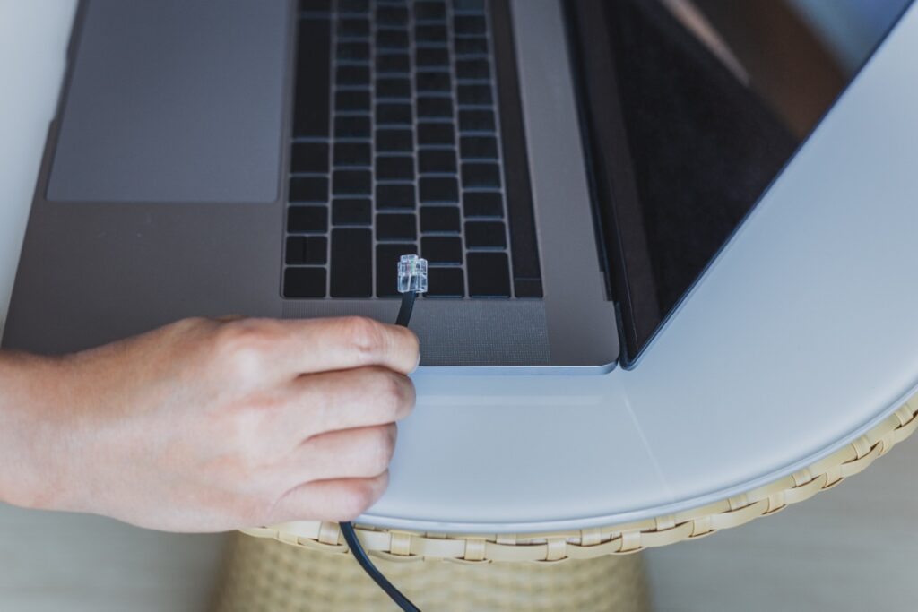 Une personne tenant un câble ethernet sur un ordinateur