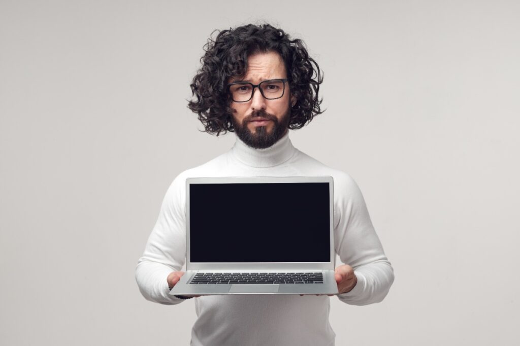 Un homme barbu tenant un ordinateur portable