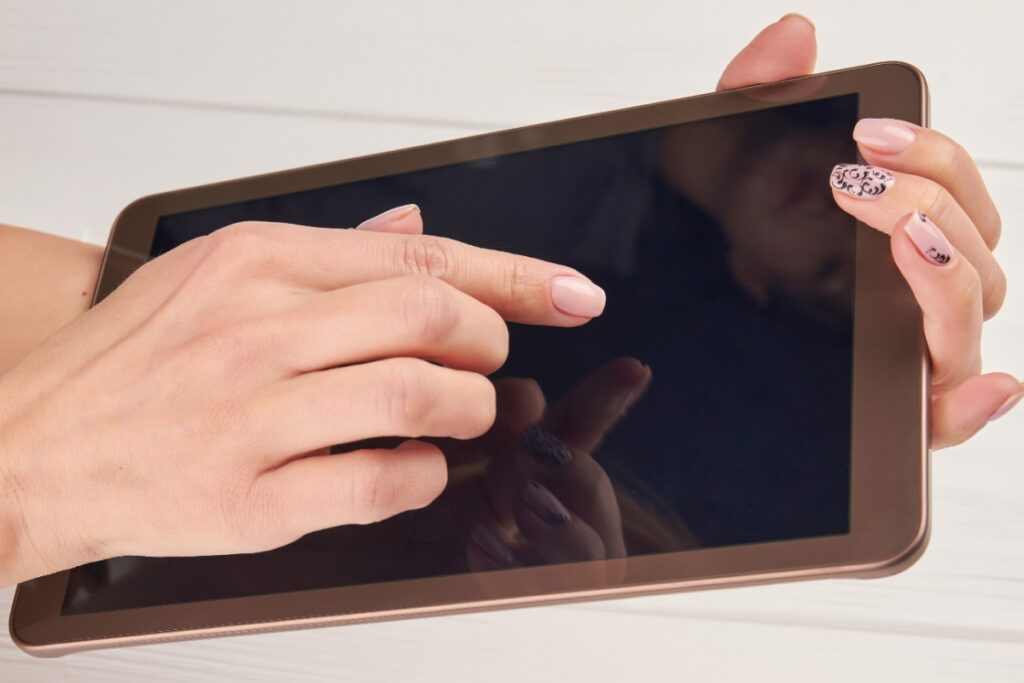 Une main touchant l'écran d'une tablette