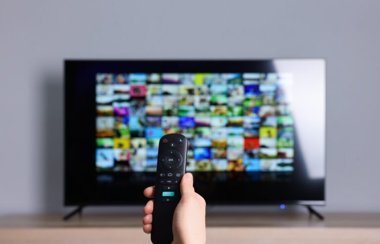 Une personne qui tient une télécommande et allume la télé