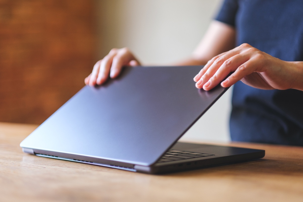 Une personne ouvrant son ordinateur sur la table
