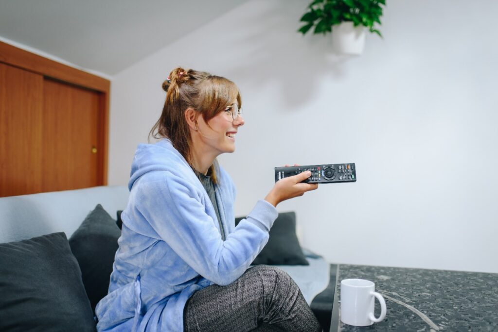 Une femme souriante tenant la télécommande