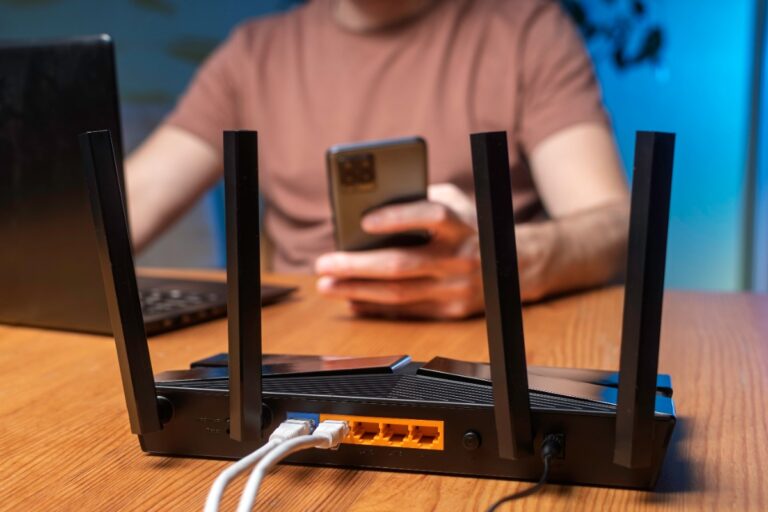 Un homme qui travaille sur un ordinateur avec un routeur wifi sur la table