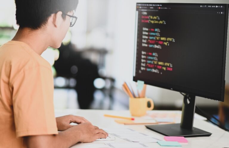 Un jeune homme tapant du code sur un ordinateur