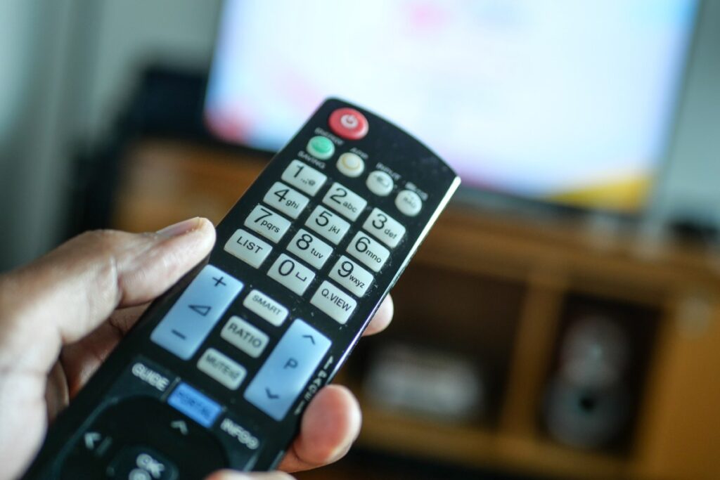 Main qui tient une télécommande et allume la télévision